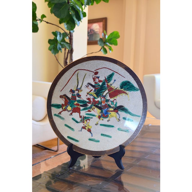 CHINESE CRACKLE-GLAZED CERAMIC CHARGER Era: Late 19th Century Style: Warrior Scene with Horses OVERVIEW: A substantial...