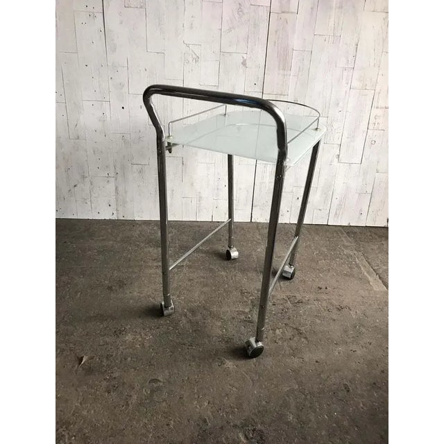 This 1960s vintage French Regency-style tea cart. The frame features two levels. The top-level features a glass shelf with...