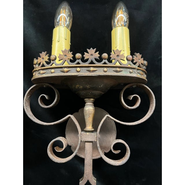 Pair of 1920s Spanish Revival wall sconces featuring intricate Spanish scrolling and crown details, each holding two...