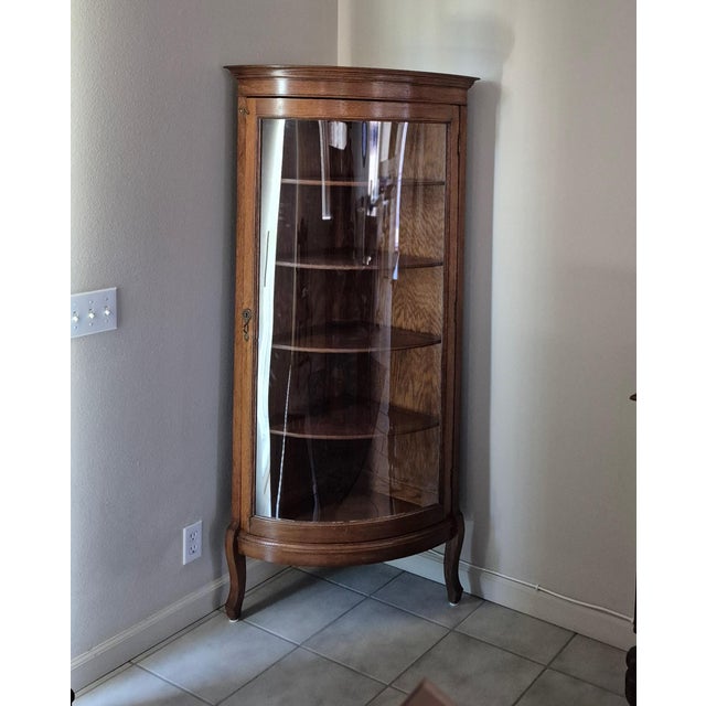 This is a vintage or antique American oak corner curio cabinet, likely dating from the early 20th century. Key Visual...