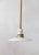 A contemporary pendant light with a rope-covered cord, small milk glass saucer shade, and ceramic and brass canopy....