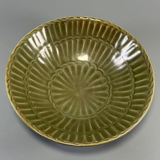 This bowl features distinctive radiating rib‑carved details both inside and out, covered with rich olive‑green celadon...