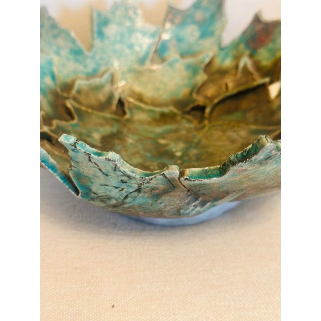 A striking hand-formed ceramic bowl inspired by layered leaves or unfolding petals, featuring dramatic sculptural edges...