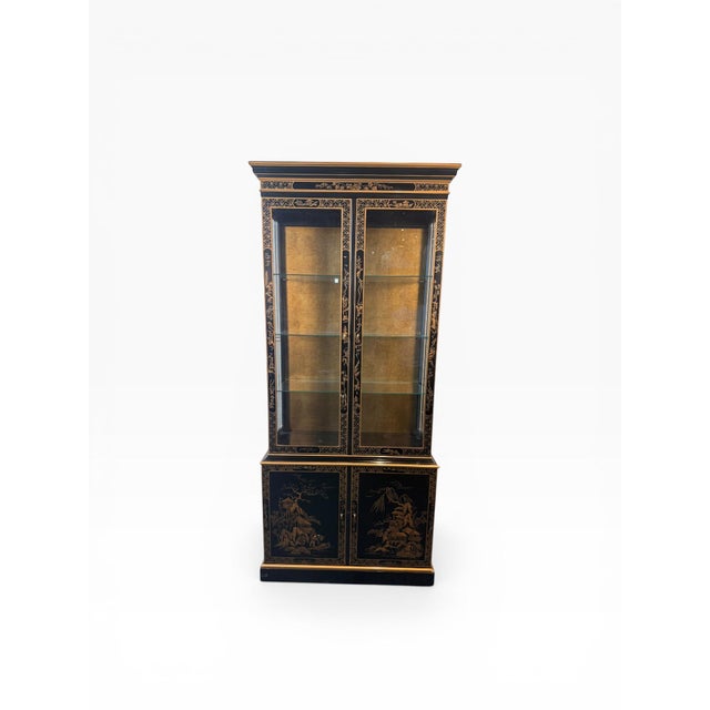 A striking Drexel Heritage illuminated display cabinet showcasing classic Chinoiserie design with intricate gilt...