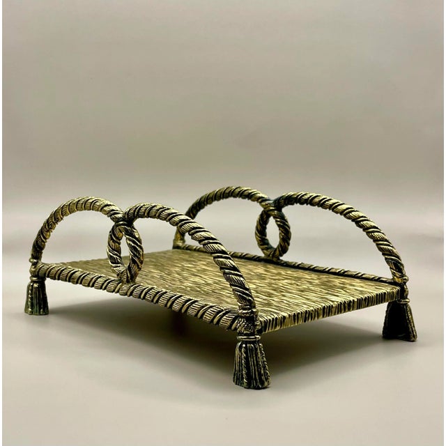 A vintage textured brass tray edged with looped brass ropes ending in tassel feet which could be used for holding towels,...
