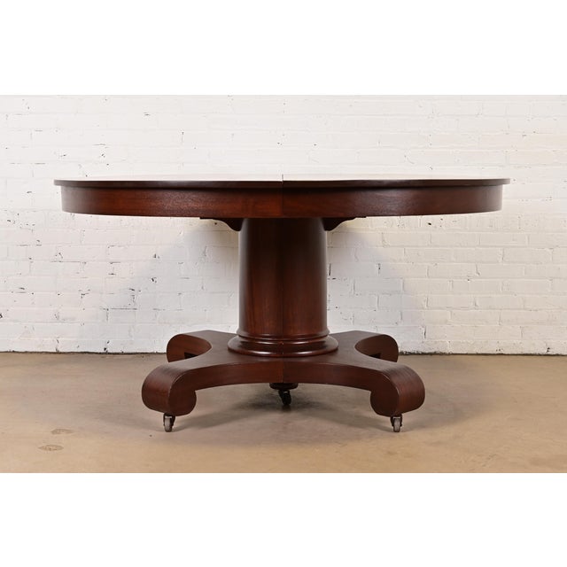 An outstanding antique American Empire or Victorian style carved mahogany pedestal extension dining table In the manner of...