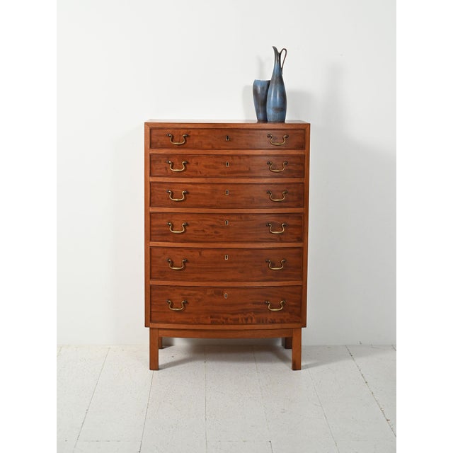 A 1940s–1950s mahogany chest of drawers with contoured brass handles, spacious drawers, and balanced proportions. An...