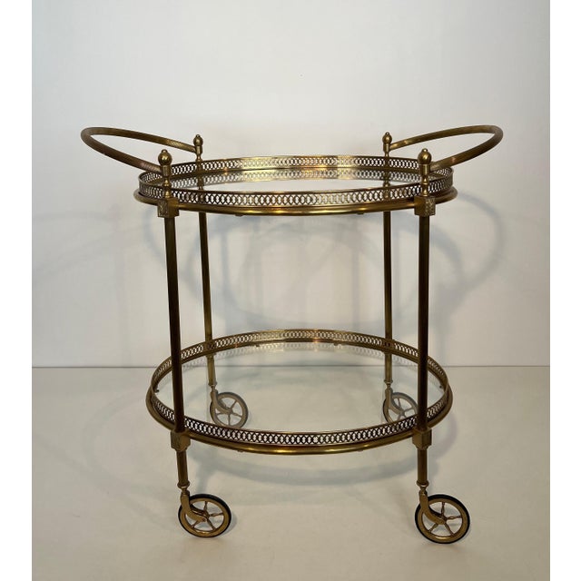 This beautiful and elegant neoclassical style oval bar cart is made of brass with glass tops. It is a French work by...