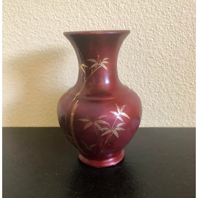 This vase is made of glass and it was hand painted. It also is painted on the inside a cooper color and has a bamboo motif...