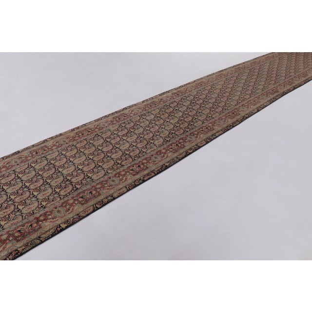 Hand-knotted in wool and originating from Persia circa 1950-1970, this 4x23 vintage Sarouk runner is a refined example of...