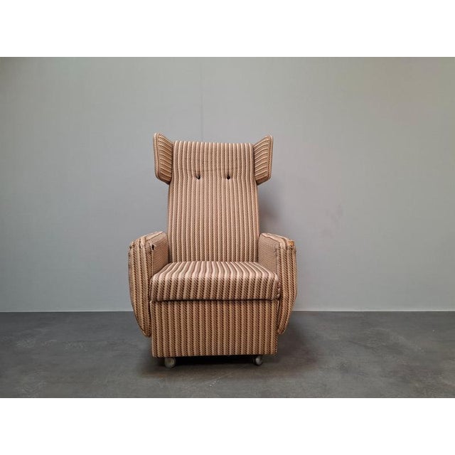 An authentic Mid-Century Modern wingback lounge armchair produced in Czechoslovakia during the 1960s. The chair features a...