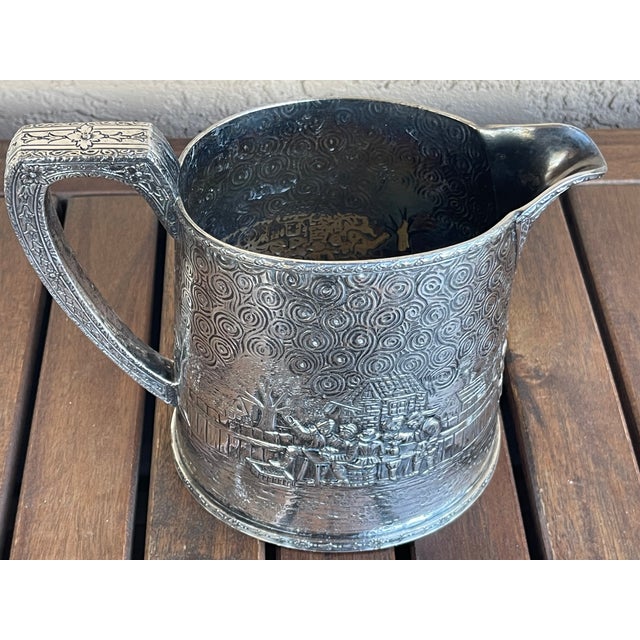 This is a Derby S.P. Co. International figural repousse village silverplate water pitcher which works well as a vase. This...