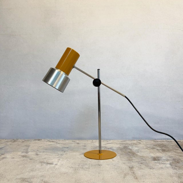 An Italian desk lamp by Prova. The cylindrical head is enamelled in mustard yellow and terminates in a wider, spun brushed...