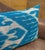 Angular chevron shapes and sharp zigzag lines expand outward from a wide open white center field, all woven in sky blue...