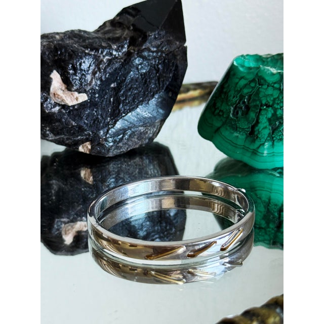 Vintage Italian sterling silver hinged bangle bracelet featuring a high polish finish and sculptural bypass design. The...
