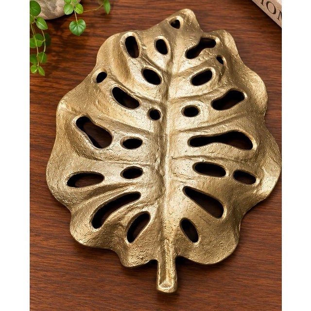A striking sculptural monstera leaf bowl or decorative tray with a beautifully rich gold finish and substantial 2.6-pound...