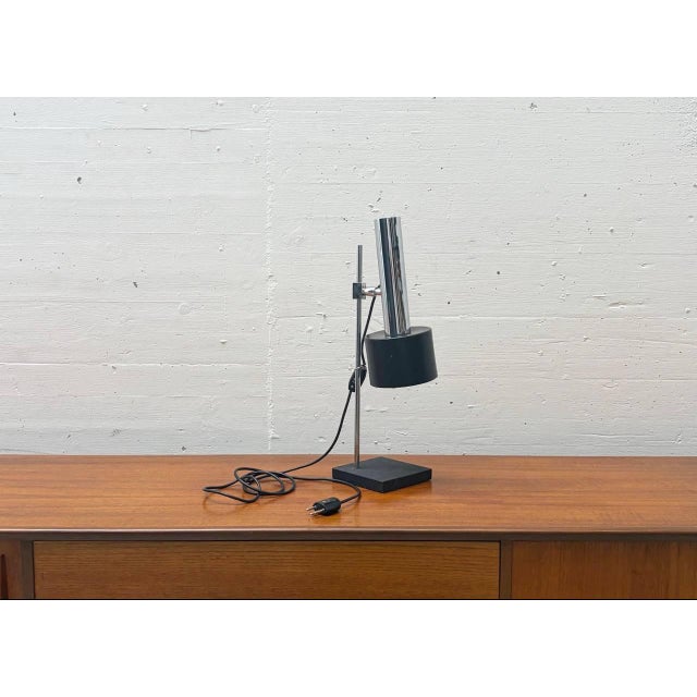 A typical 1970s table lamp with a clean, functional design. The lamp combines a chrome-plated metal frame with a...