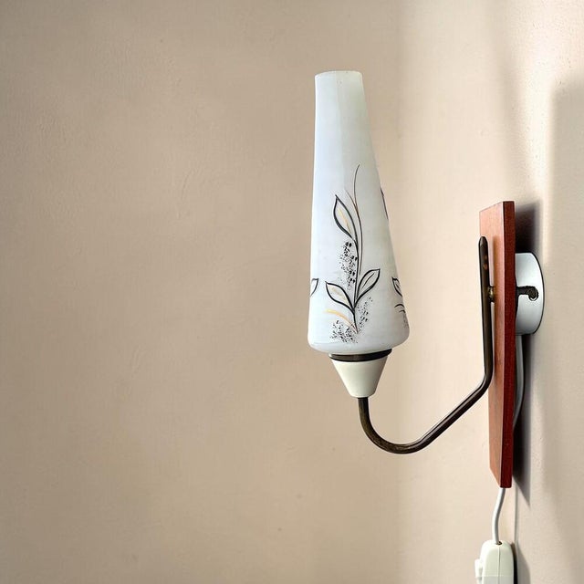A vintage mid-century wall sconce featuring a stunning cone shaped opaline glass lampshade, painted white metal support,...