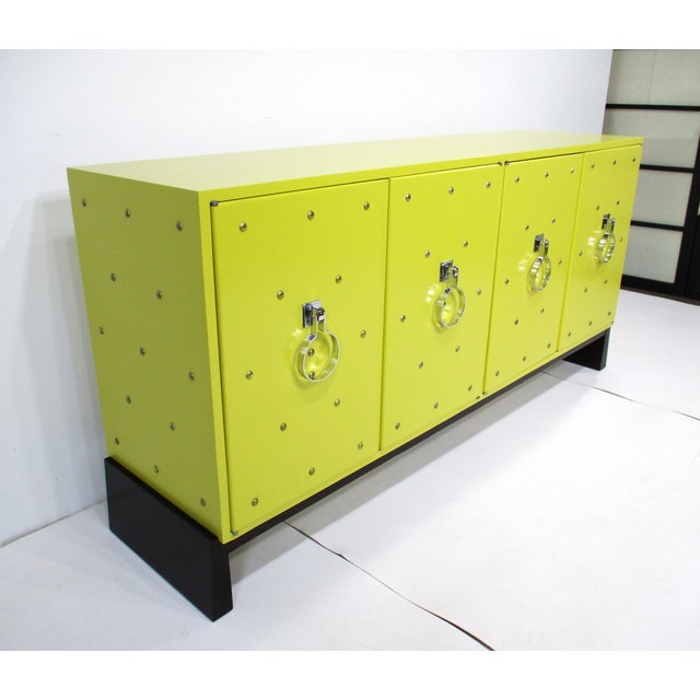 A stunning and luxurious chrome studded lemon-yellow credenza sideboard with four doors having heavy chromed handcuff...