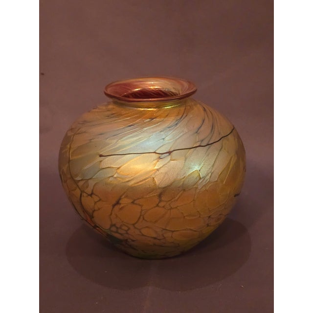 This is an exquisite art glass vase in shades of gold and burnt amber. It also has touches of light blue and streaks of...