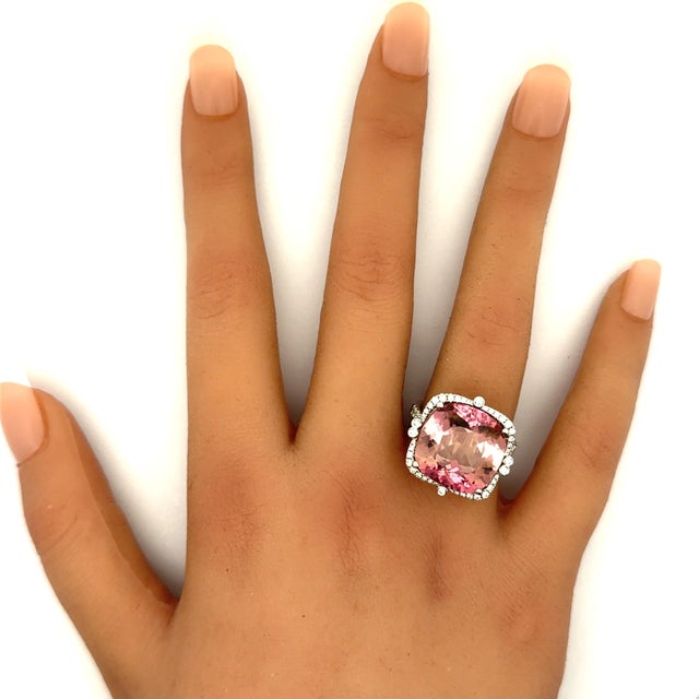 A captivating ring showcasing a 13.80-carat oval pink tourmaline, exuding vibrant pink color and glow. Surrounding the...