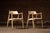 Sculptural mid century modern dining armchairs executed in walnut with tapered round legs, integrated curved armrests, and...