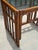 A vintage 1970s end table crafted from bamboo and rattan, featuring an intricate open fretwork design and a clear glass...