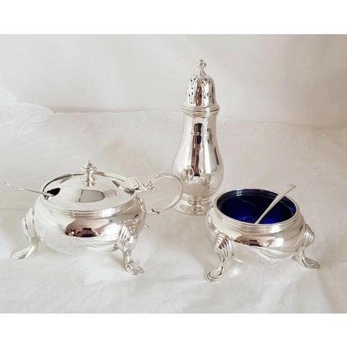A fine antique sterling silver three-piece cruet set, designed in the elegant Georgian style and comprising a mustard pot,...