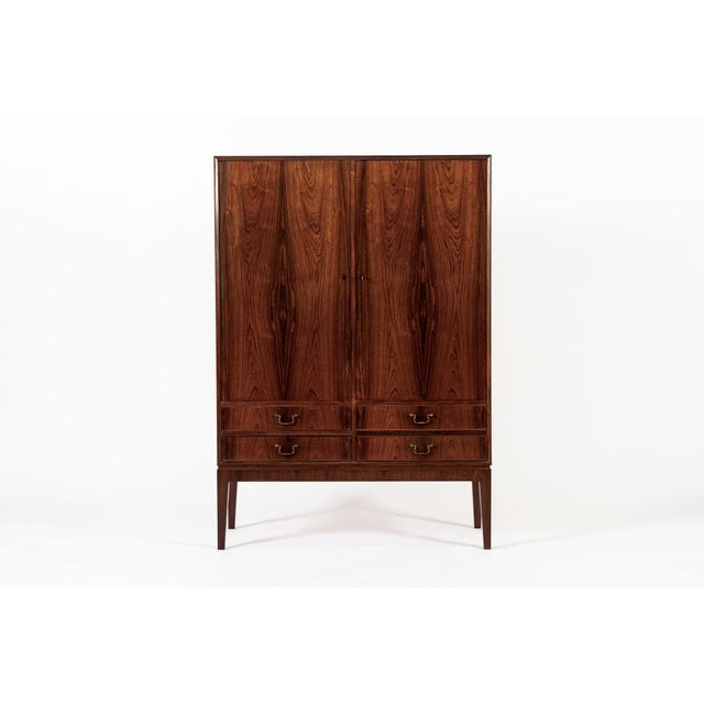 This exceptional vintage mid century Danish modern rosewood cabinet in the manner of Kaare Klint is circa 1960. This tall...