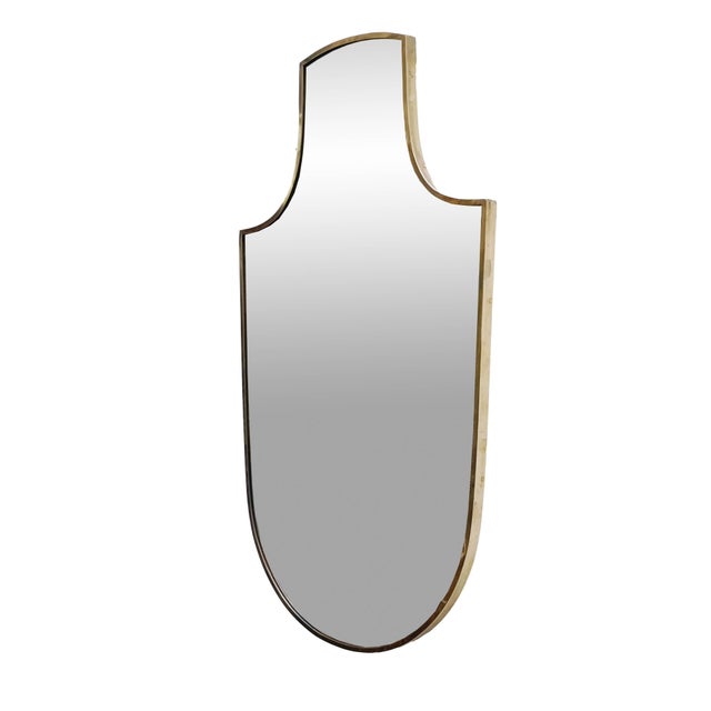 1950s shield wall mirror with rounded edges and brass frame. The mirror is classic in shape, in good condition, and has a...
