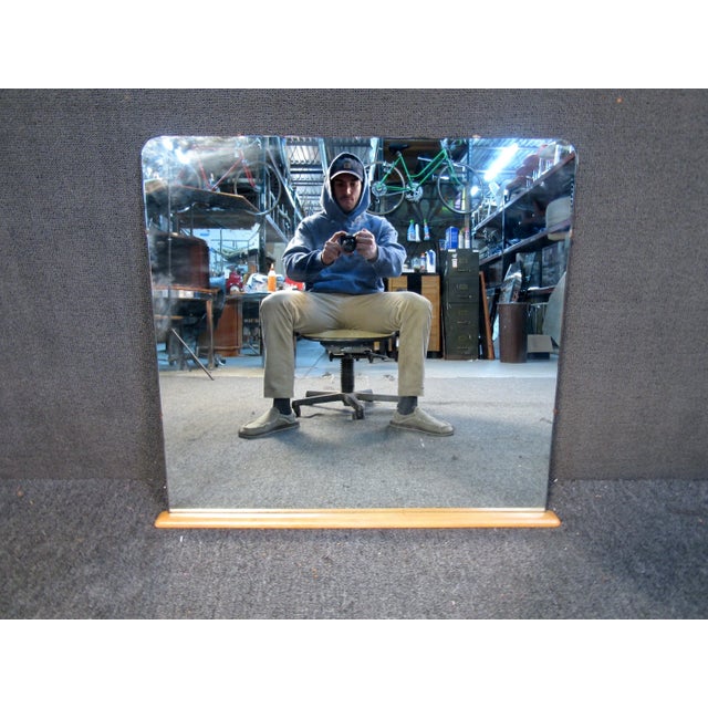 Simple and stylish vintage frameless vanity mirror. This piece features no frame and a wooden base. The mirror is held...
