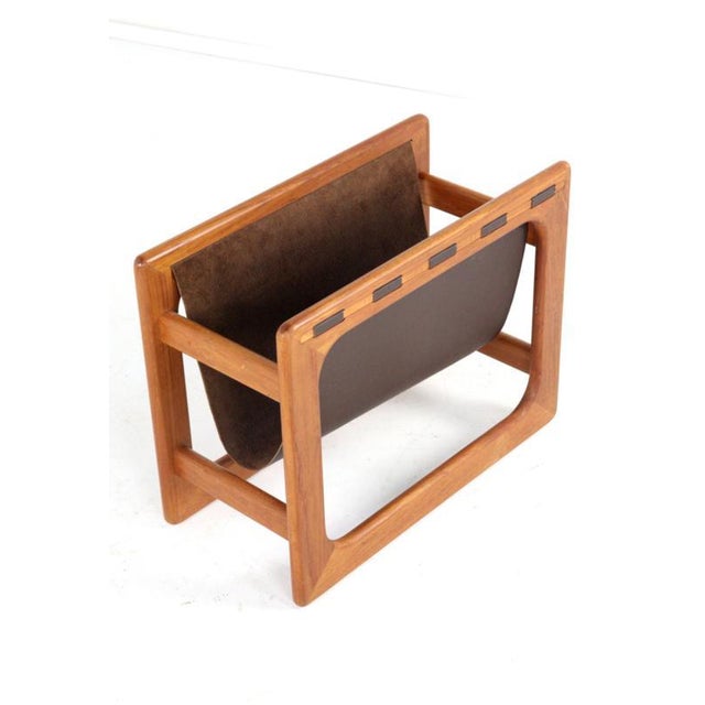 Lovely magazine rack with a solid teak frame and stylish leather. Cool and typical Danish design with warm-colored teak...