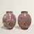 Carved from deeply saturated red marble threaded with restless white and gray veining, the urns read less as objects than...