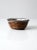 This hand-crafted studio pottery bowl features a warm brown-washed exterior glaze, accented by a bold black rim. The...