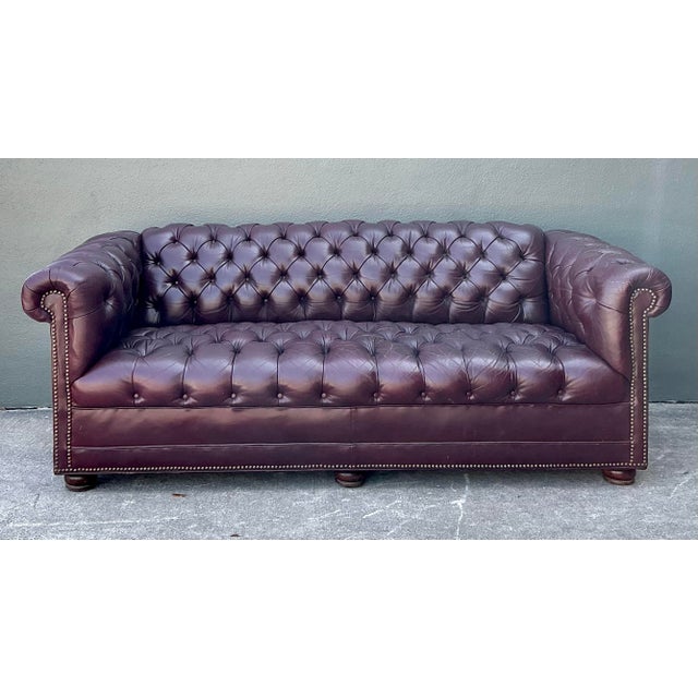 This stately vintage Chesterfield sofa captures the timeless elegance of a classic English library or a sophisticated...