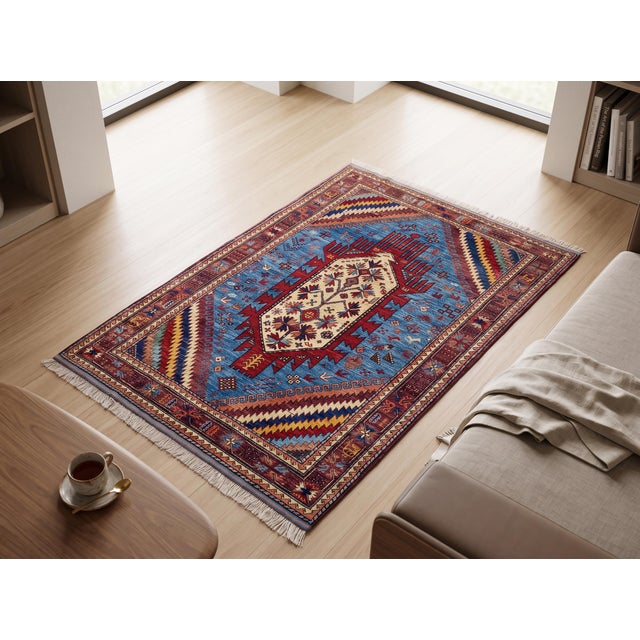An elongated ivory medallion with crimson hooked "comb" finials anchors the sky-blue field of this hand-knotted wool rug,...