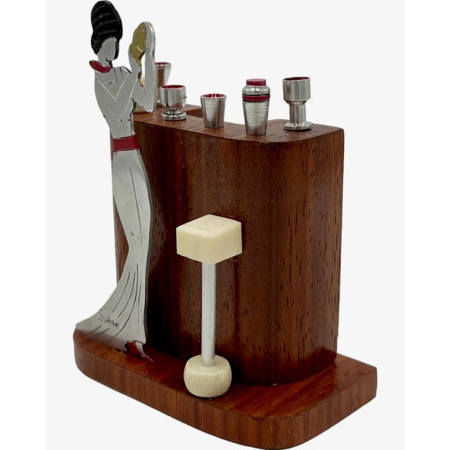 A distinctive Art Deco cocktail set attributed to Sudre, featuring a stylized female bartender in polished metal, poised...