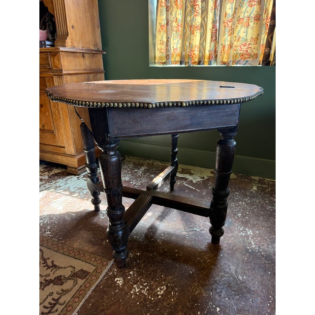 Antique English Jacobean-style oak drop-leaf table featuring a unique shaped top, turned legs, and a distinctive nailhead...