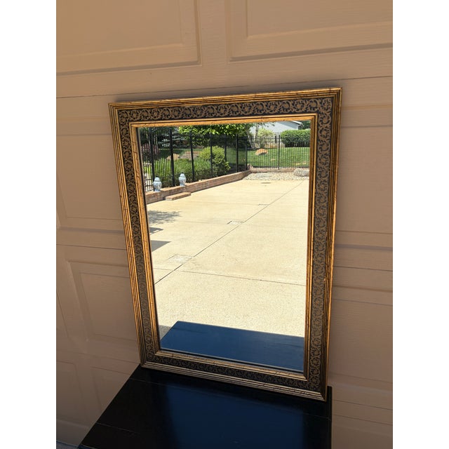 An elegant Neoclassical or Regency style giltwood mirror featuring a richly painted frame with scrolling acanthus details...