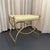 This decorative Hollywood Regency vanity stool features a sweeping, brass toned frame that follows the format of an...