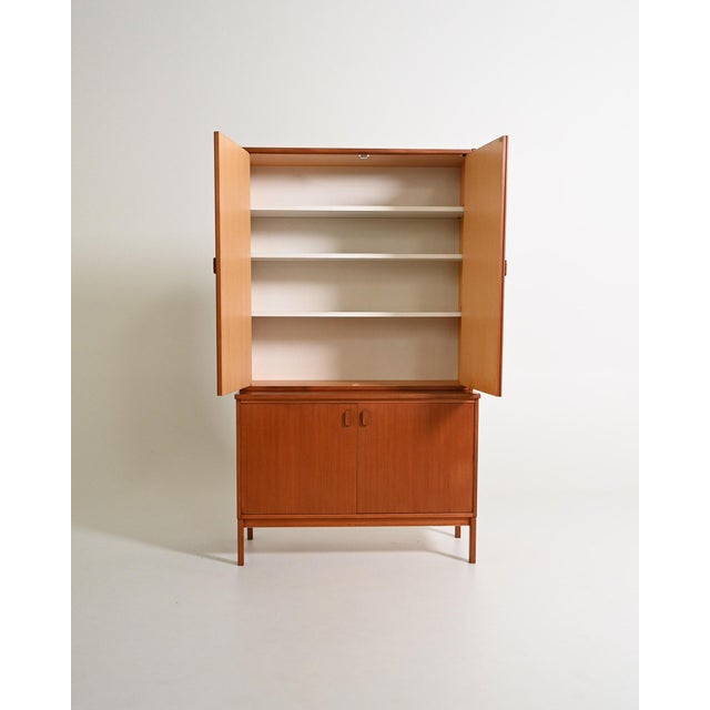 Two-piece teak wardrobe with four hinged doors. Scandinavian production, 1960s. Featuring balanced proportions and a...