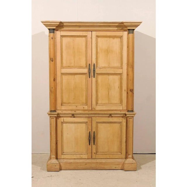 An exquisitely tall English natural wood vintage cabinet. This tall cabinet with a very linear profile features two...