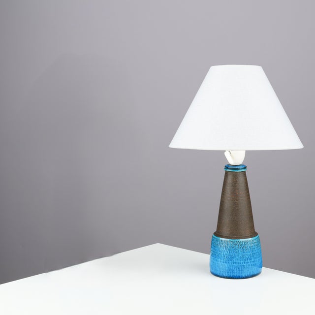 Table lamp made of partly blue-glazed stoneware with relief pattern. Signed “HAK" & "Denmark” on the bottom. Signature...