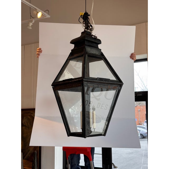 A hanging lantern of faceted, tapering form with a stepped, pagoda-like top and glazed sides. The lantern is constructed...