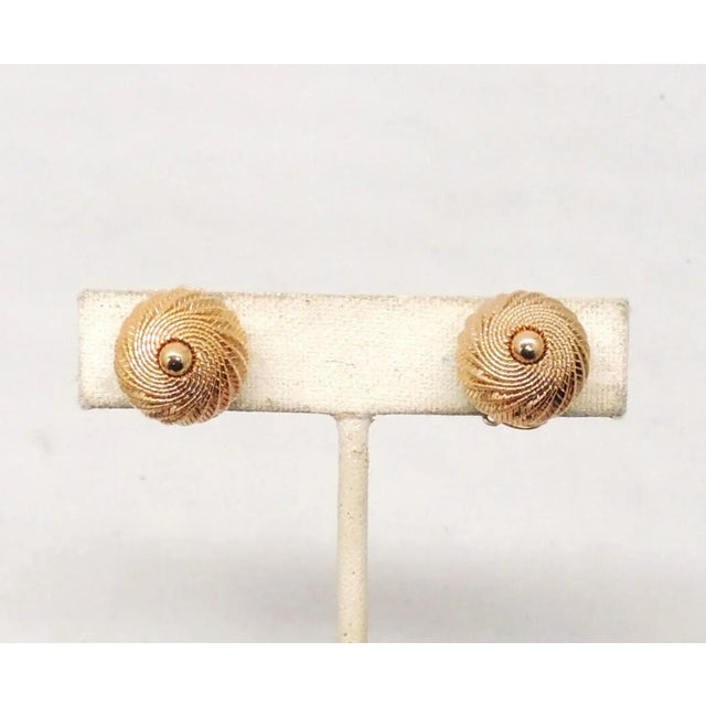 This is part of Chairish’s Costume Jewelry assortment. Circa 1960s goldtone domed spiral clip earrings. Marked "Napier...