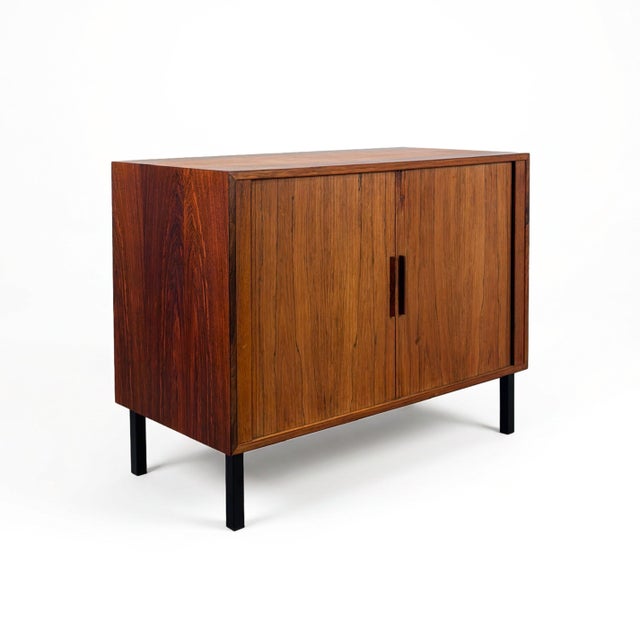 A stunning small cabinet featuring smooth-gliding tambour doors that slide around the back to reveal storage with a...
