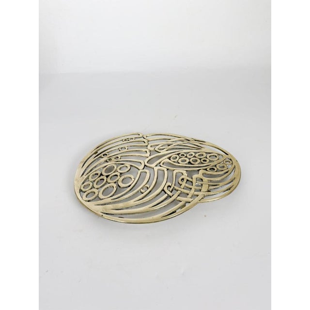 Elegant French brass trivet featuring an openwork Art Nouveau design inspired by flowing botanical forms and stylized seed...