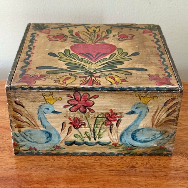 Charming rustic folk art cigar box painted by hand in bright shades of blue, pink, green, and yellow. Surrounded by a...