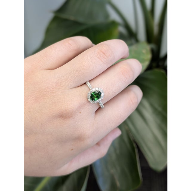 Radiating timeless elegance, this exquisite ring features a dazzling 0.77-carat oval center stone, perfectly framed by a...