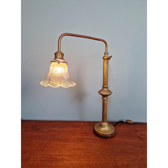 Large brass desk lamp on a wooden base with a clear, fluted glass shade, dating from approximately the 1930s. This unique...